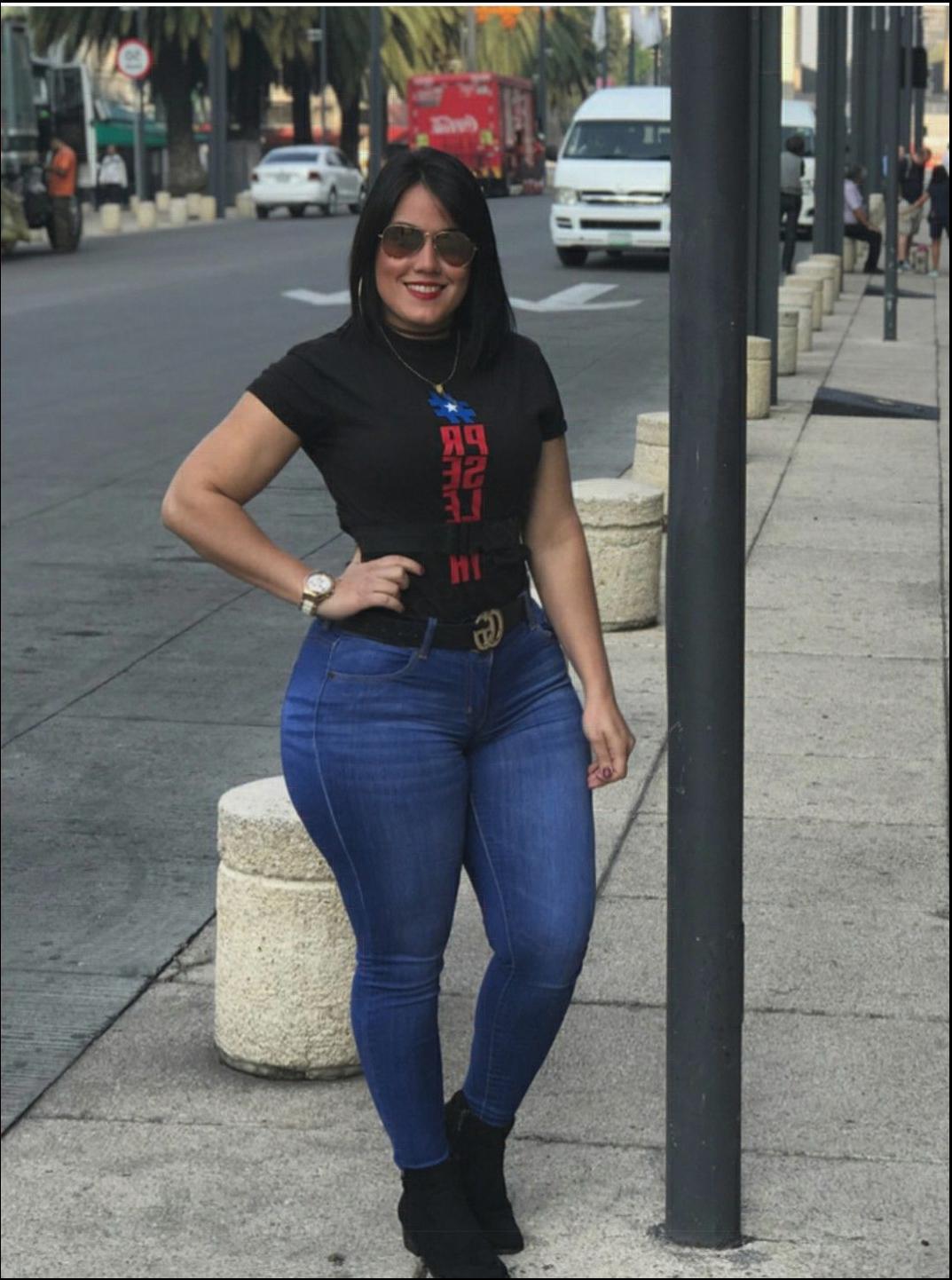 a woman is standing on a sidewalk with a cell phone