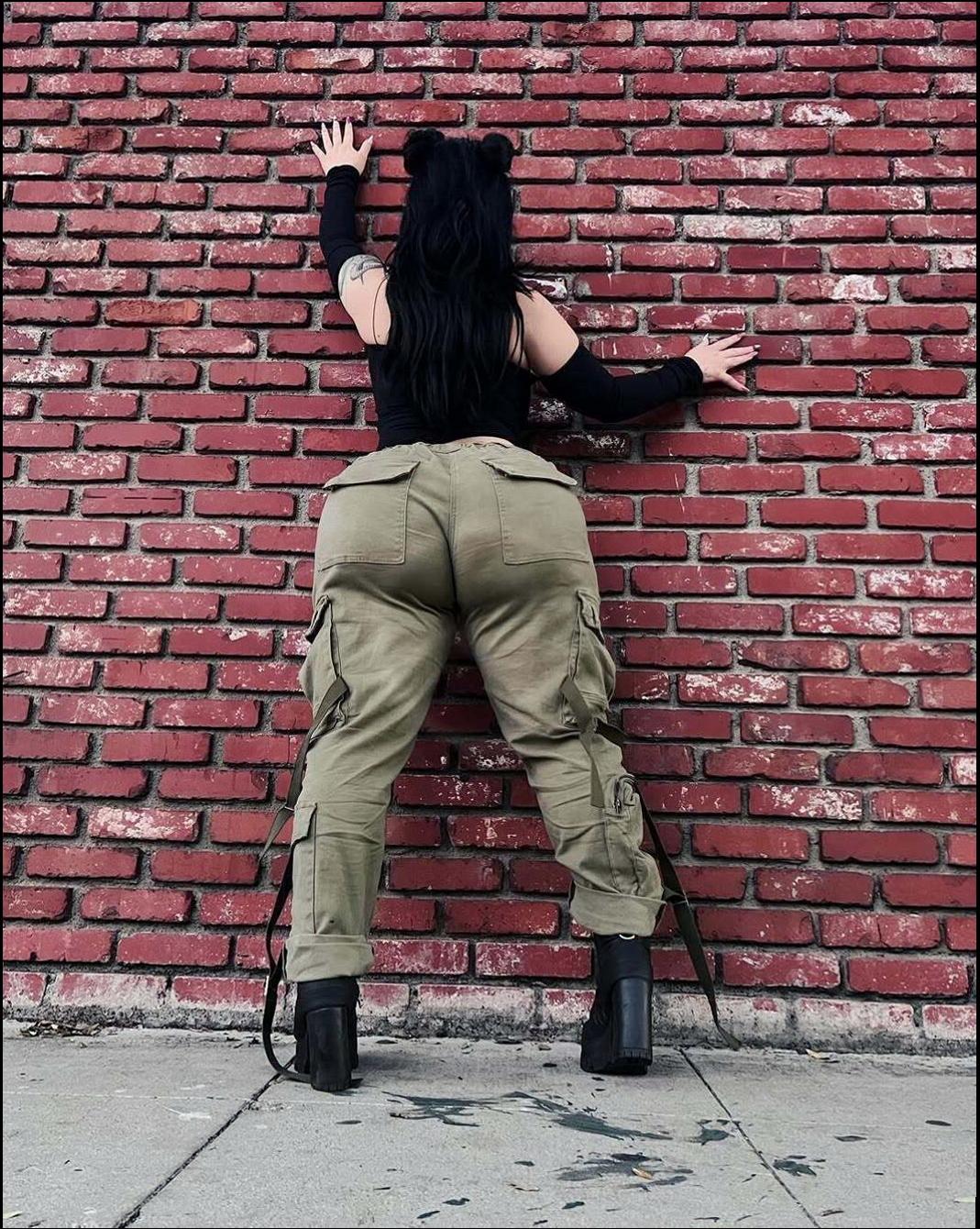 a man is standing on a brick wall with a cell phone