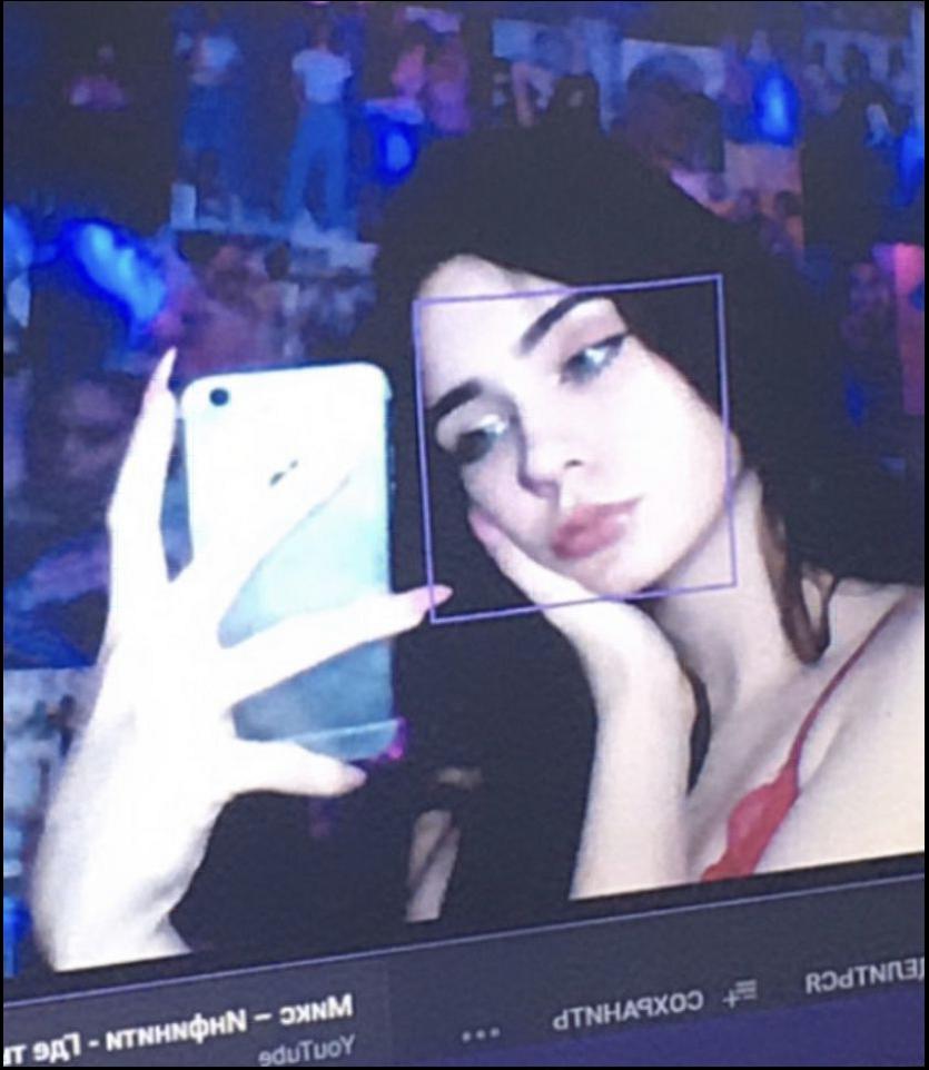 a woman holding a cell phone in front of a tv