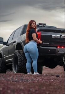 a woman standing in the dirt with a truck