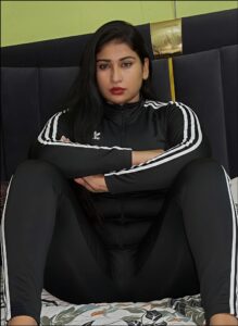 a woman is sitting on a bed with a black and white striped scarf