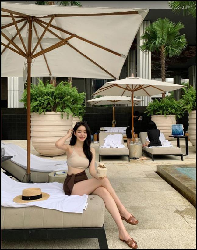 a woman sitting on a beach with a white umbrella