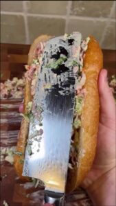 a person holding a sandwich with a knife