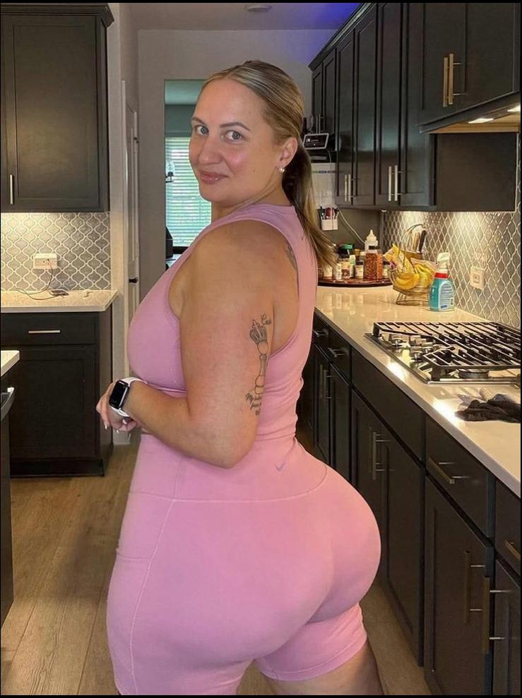 a woman in a pink dress standing in a kitchen
