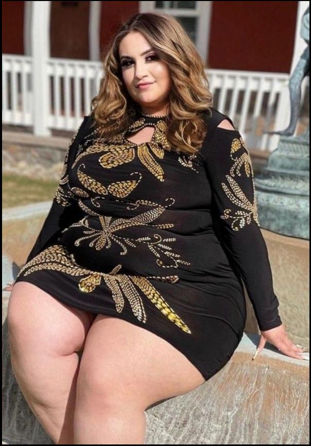 a woman in a black dress sitting on a sidewalk