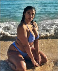a woman sitting on a beach with a surfboard