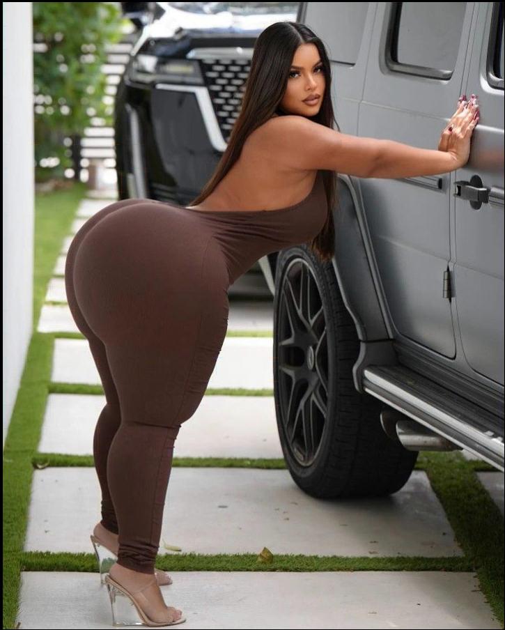 a woman in a black dress standing in front of a white truck