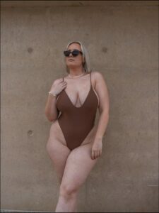 a woman in a bikini and a hat on a sidewalk