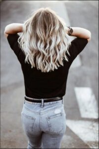 a woman is standing on a sidewalk with a black and white striped shirt