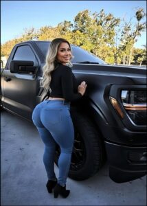 a woman is sitting on the hood of a black car