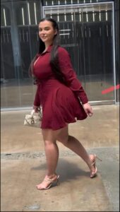 a woman standing on a sidewalk holding a red and white object