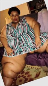 a woman is sitting on a bed with a striped blanket