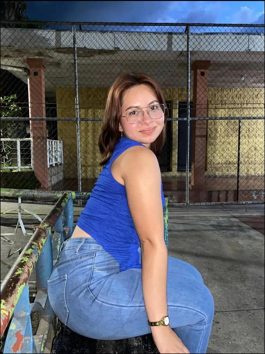 a woman sitting on a bench wearing a blue shirt