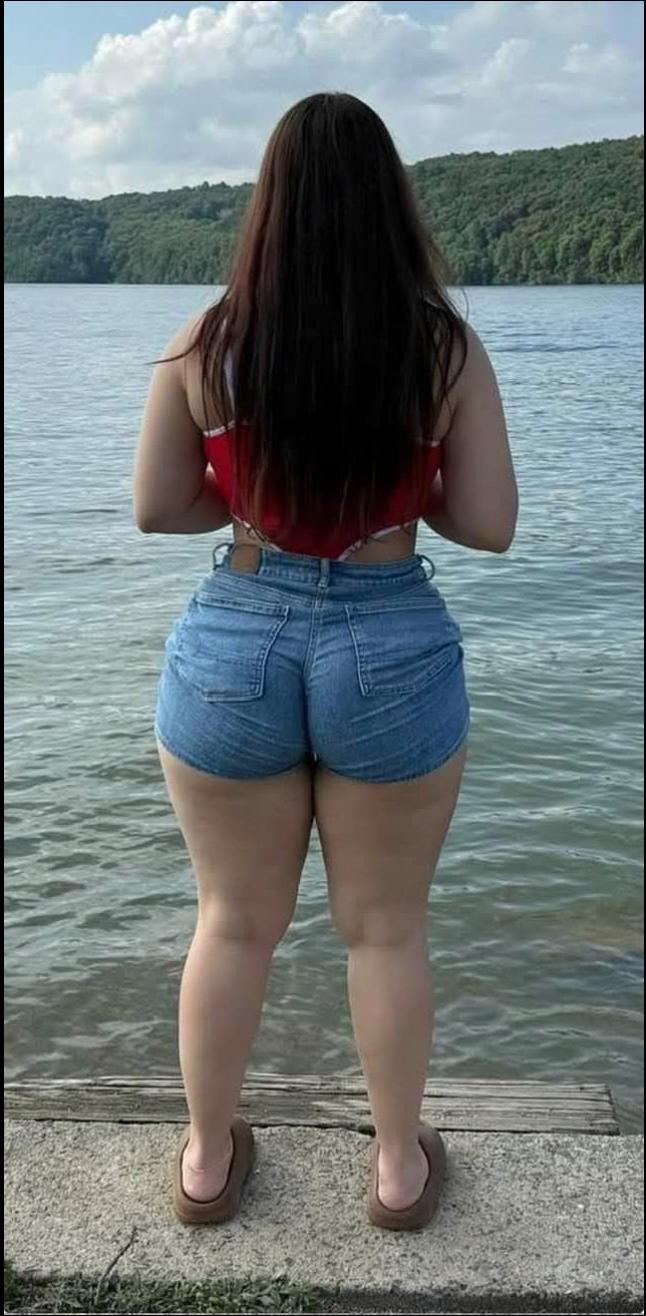 a woman is standing on a ledge near the water