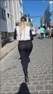 Woman in Black Leggings Walking Down a Cobblestone Street
