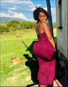 a woman in a red dress standing by a fence