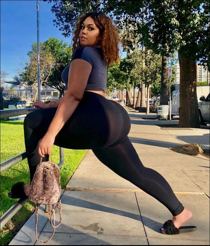 a woman is standing on a sidewalk with a bag