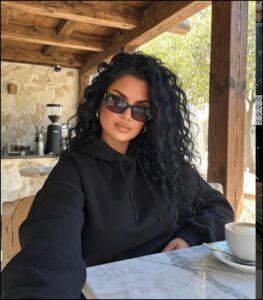Woman in Black Sunglasses and Hoodie Sitting at Cafe Table