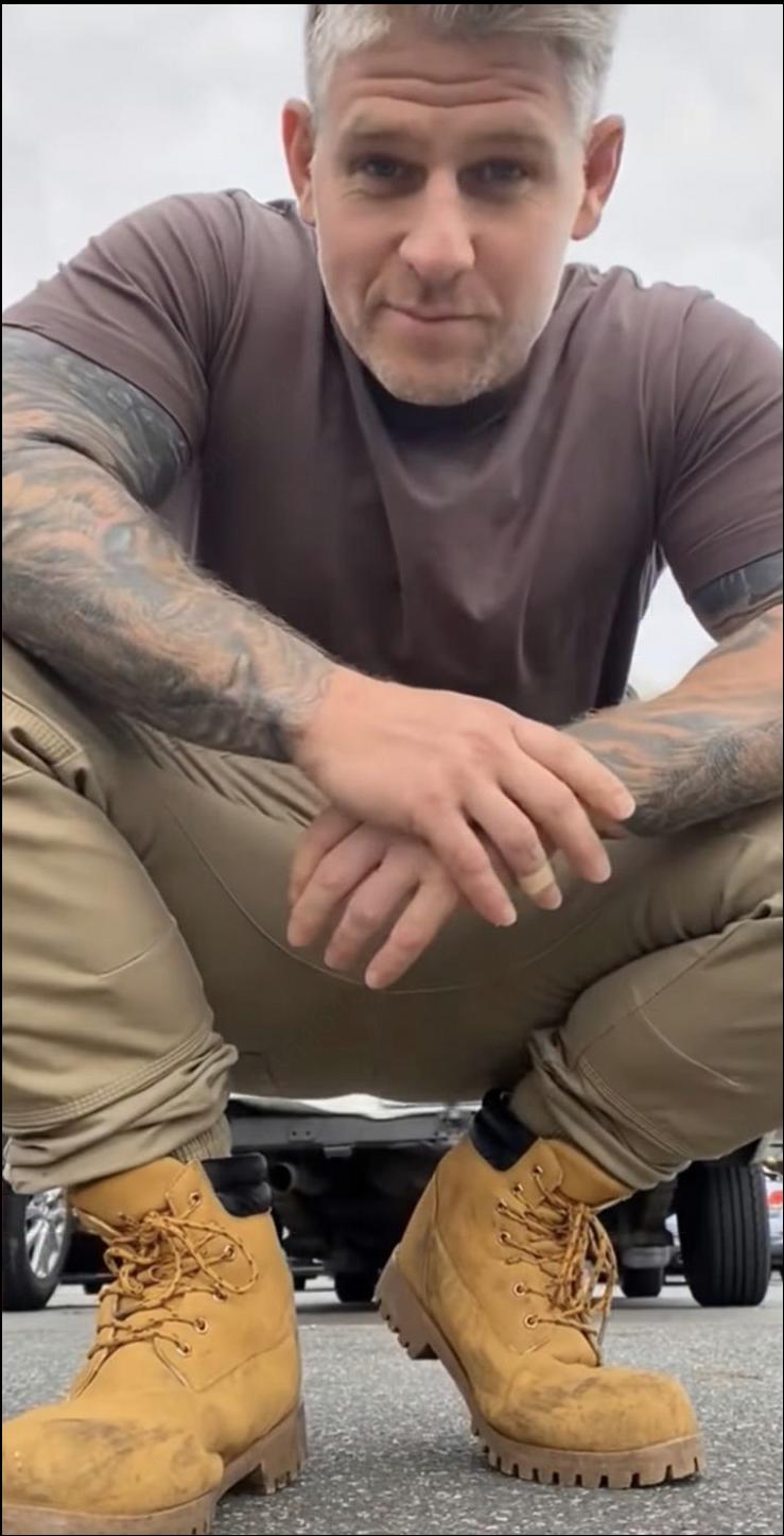 a man sitting on a sidewalk with a pair of shoes