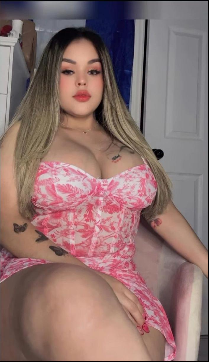 a woman in a pink dress sitting on a white bed