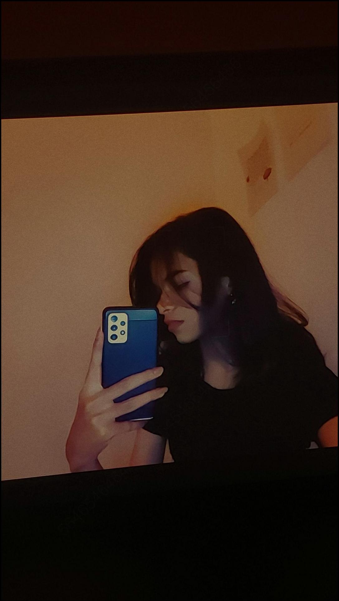 a woman is sitting on a wall looking at her cell phone