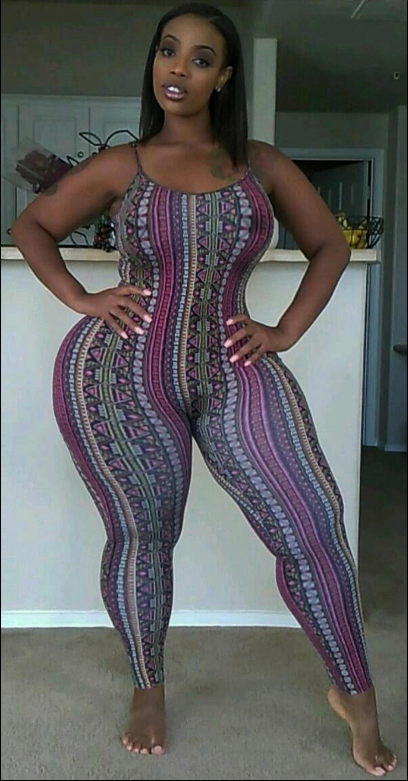 a woman in a black dress standing in a kitchen