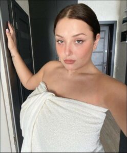 a woman is standing in a bathroom with a towel on her head