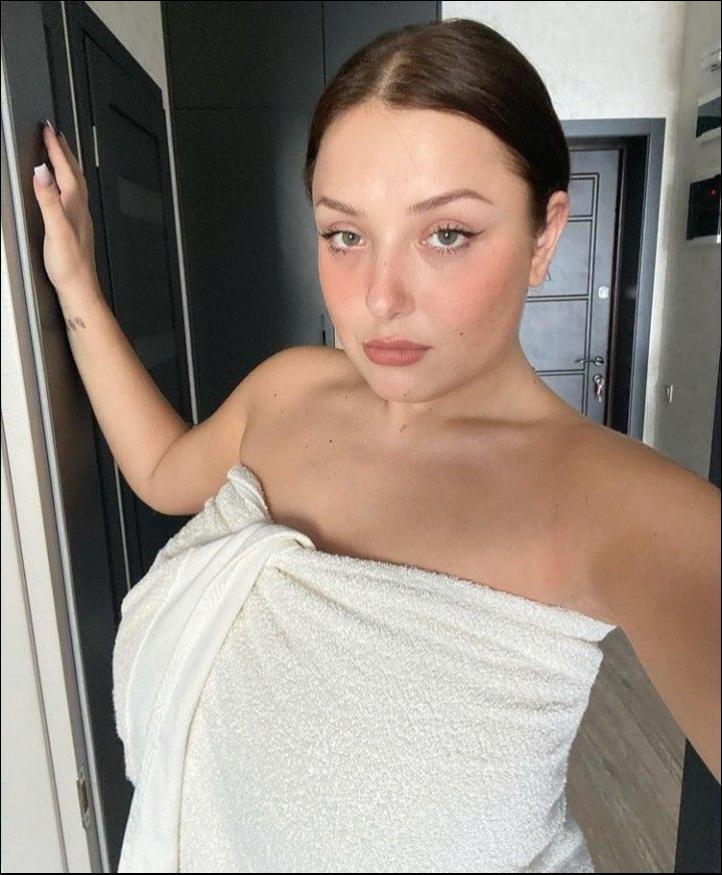 a woman is standing in a bathroom with a towel on her head