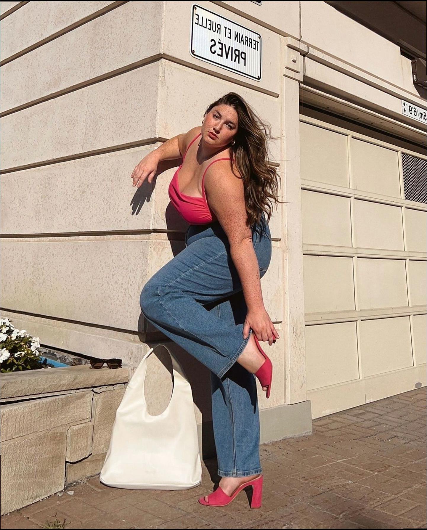 a woman is posing for a picture on a sidewalk