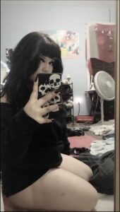 a woman is holding a cell phone in front of a wall