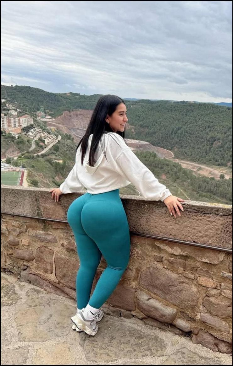 a woman is sitting on a stone wall with a blue wall