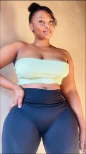 a woman is sitting on a white bed with a blue shirt