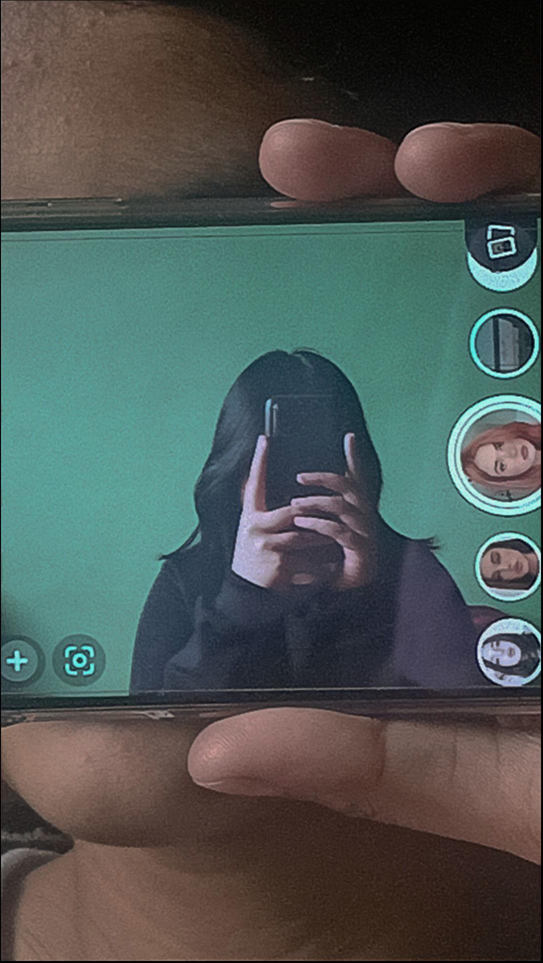 a person holding a cell phone in front of a laptop