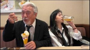 a man and a woman sitting at a table with a drink