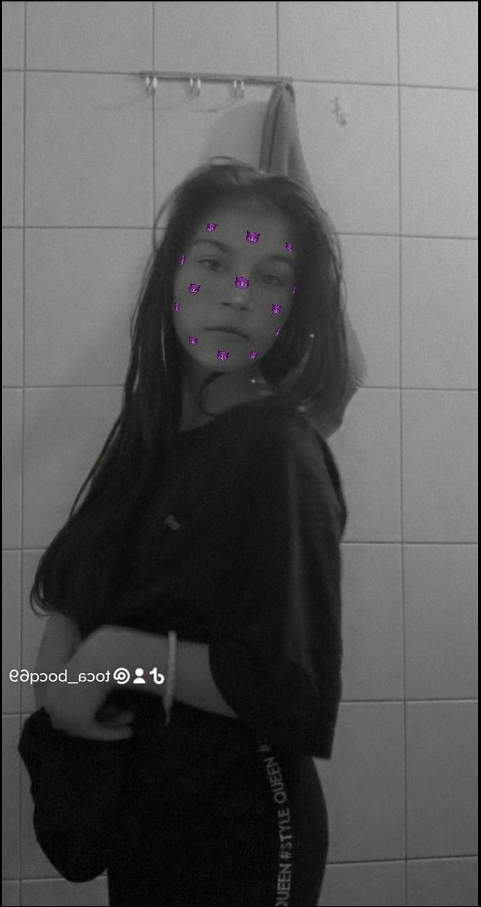 a girl with a black hair standing in front of a wall