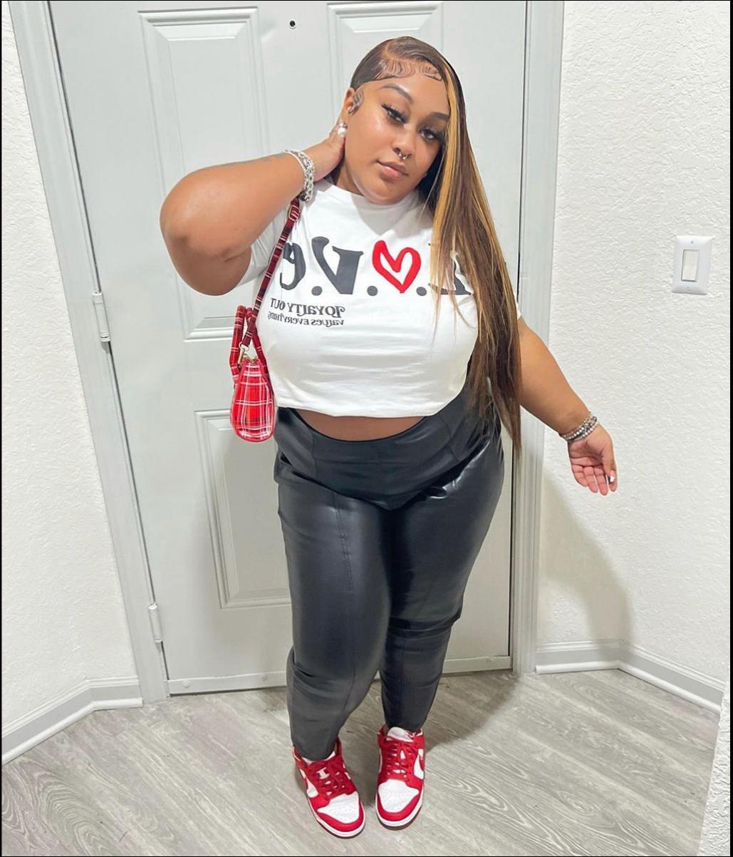 a woman in a red shirt and black pants posing for a picture