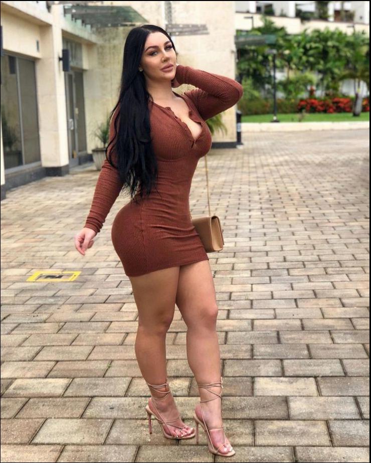 a woman in a red dress standing on a brick sidewalk