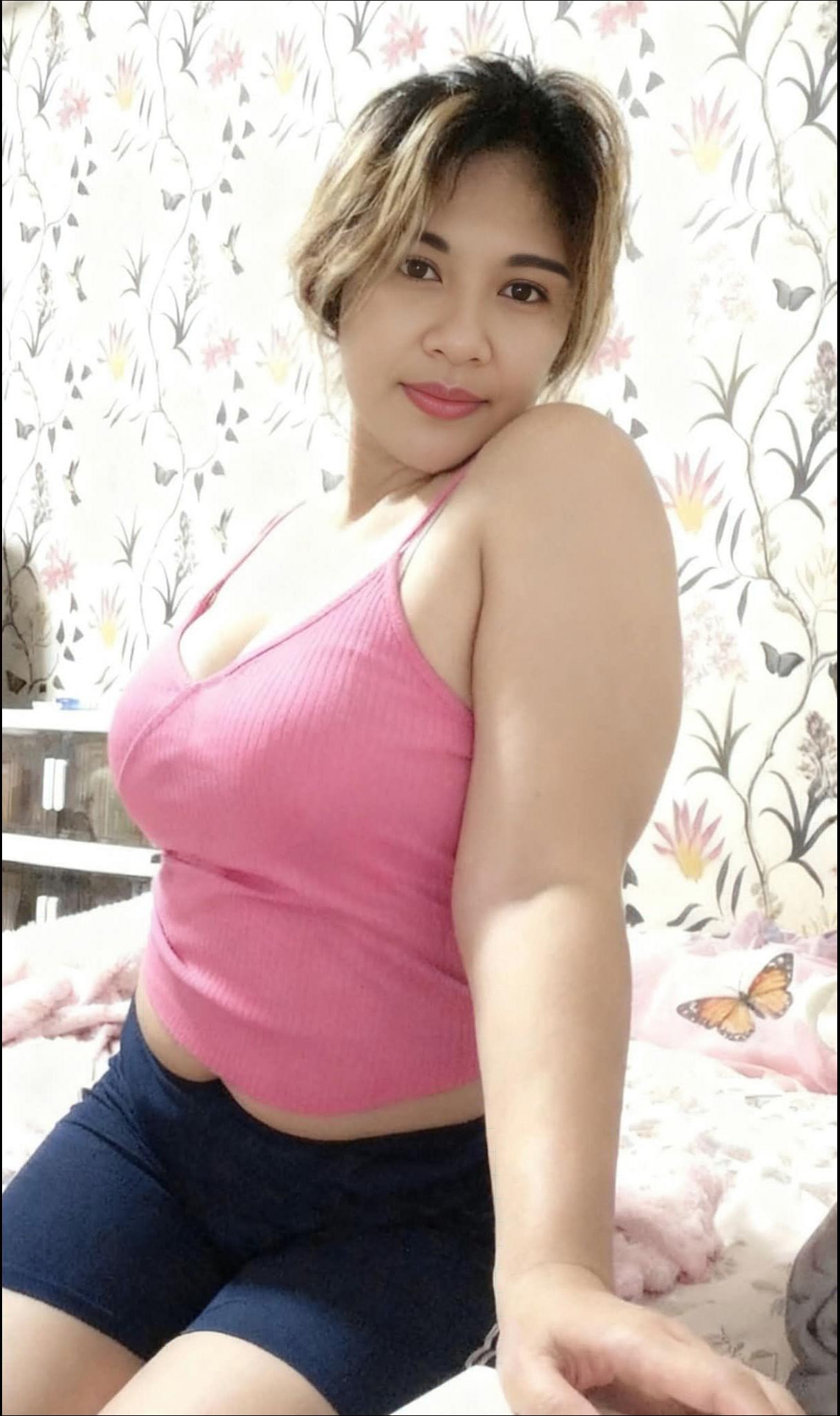 a woman is sitting on a bed with a pink flower