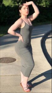 a woman in a black dress standing on a sidewalk