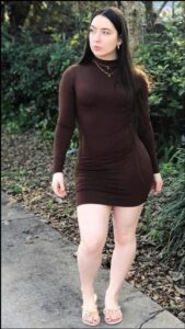 a woman in a black dress standing on a sidewalk