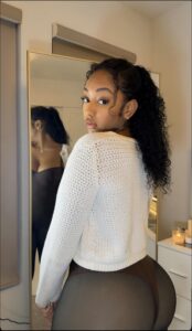 Woman in white sweater and dark bottoms poses in mirror