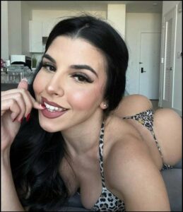 Close-up of a woman with dark hair, smiling, and wearing a leopard print bikini top.