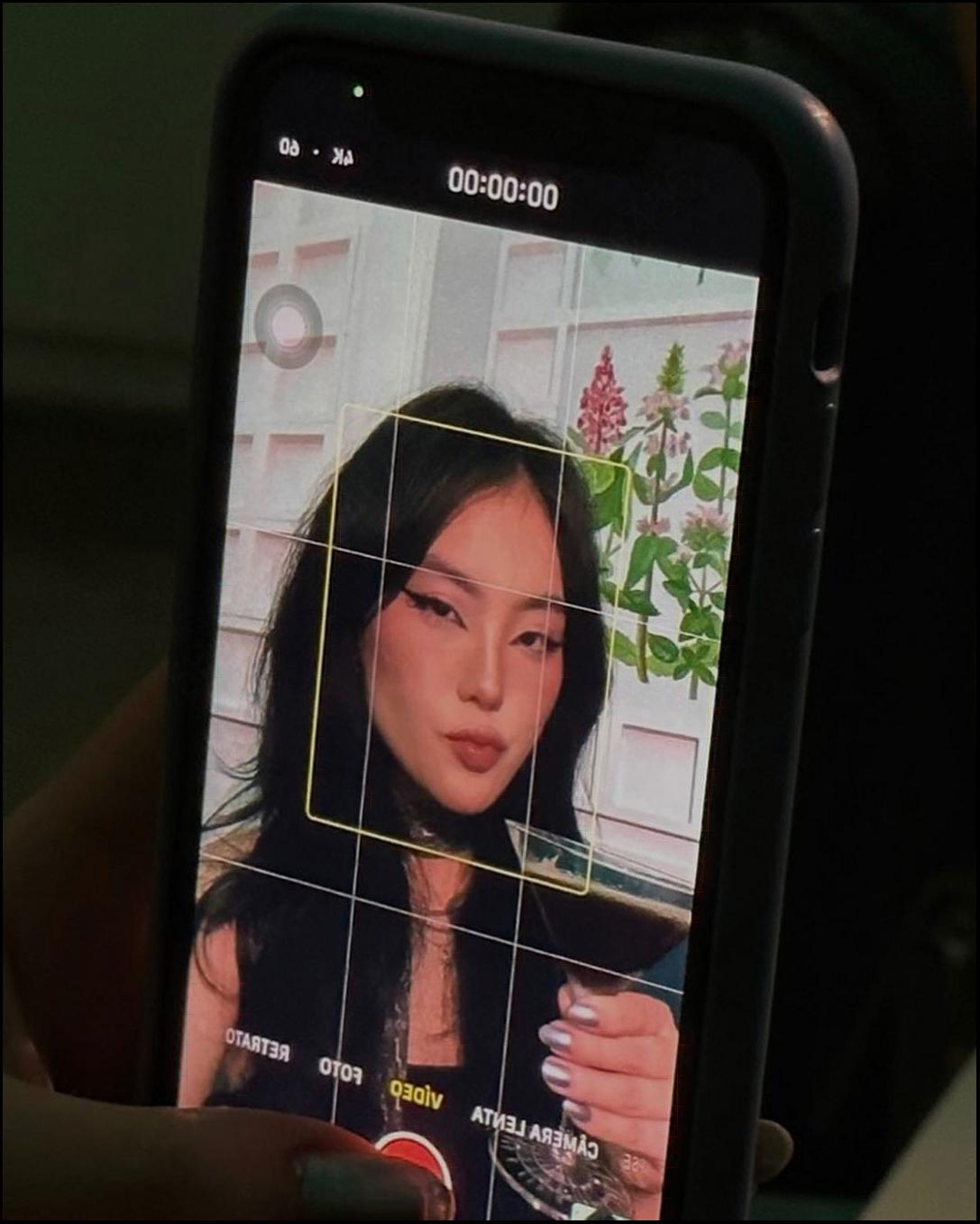 a woman holding a cell phone in front of a picture