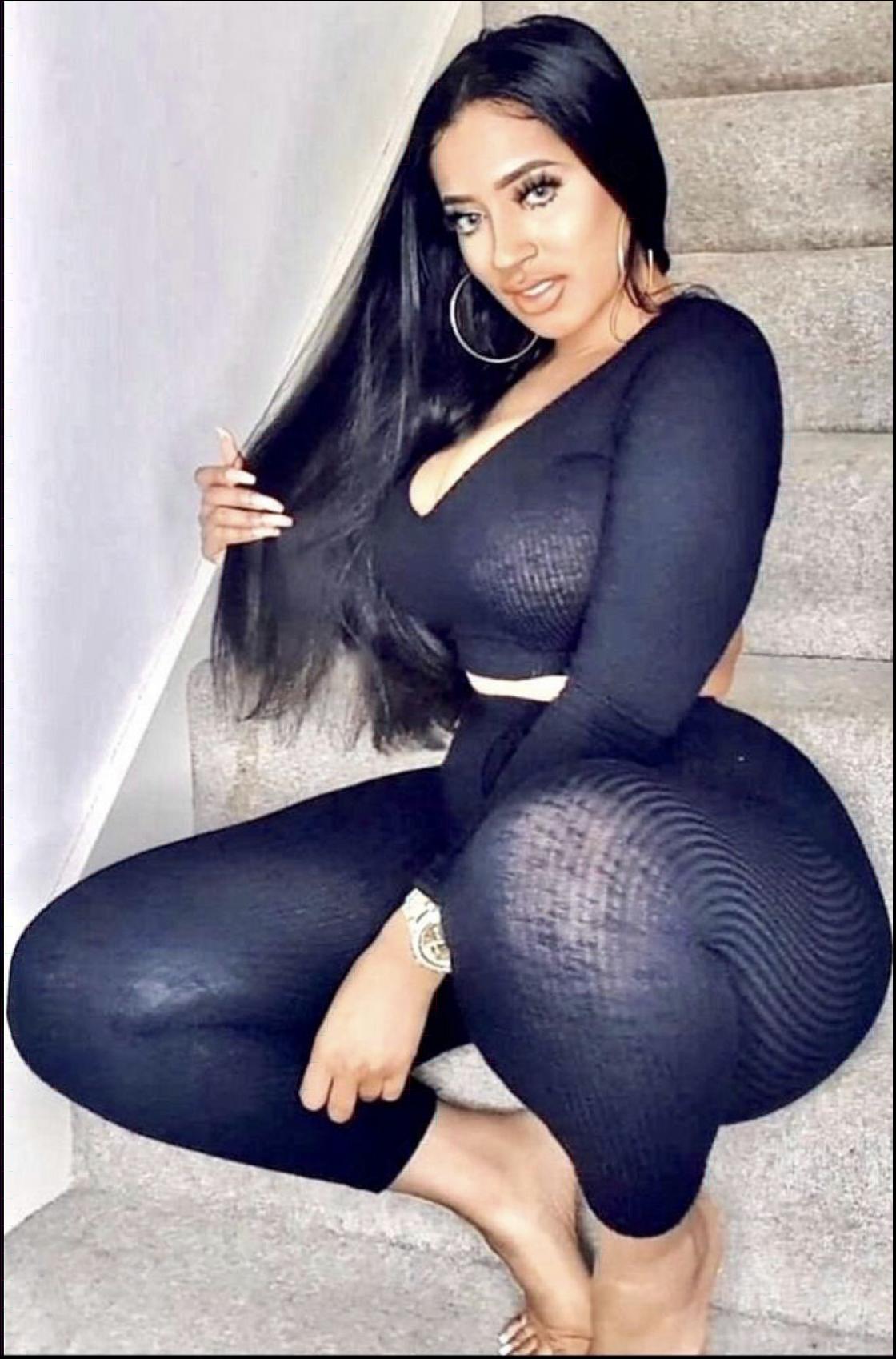 a woman in a black dress is sitting on a wall