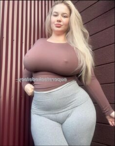 a woman is standing on a wall with a large breast