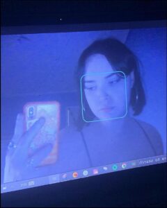 a person with a cell phone in front of a laptop