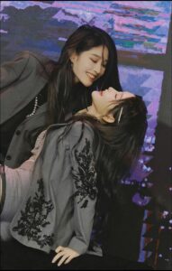 a woman is sitting on a wall with a painting