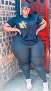 Woman in black clothing poses against a brick wall with a red door. Woman in black clothing poses against a brick wall with a red door.