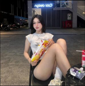 a woman sitting on a bench with a hot dog