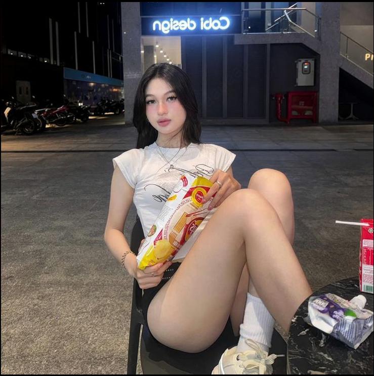 a woman sitting on a bench with a hot dog